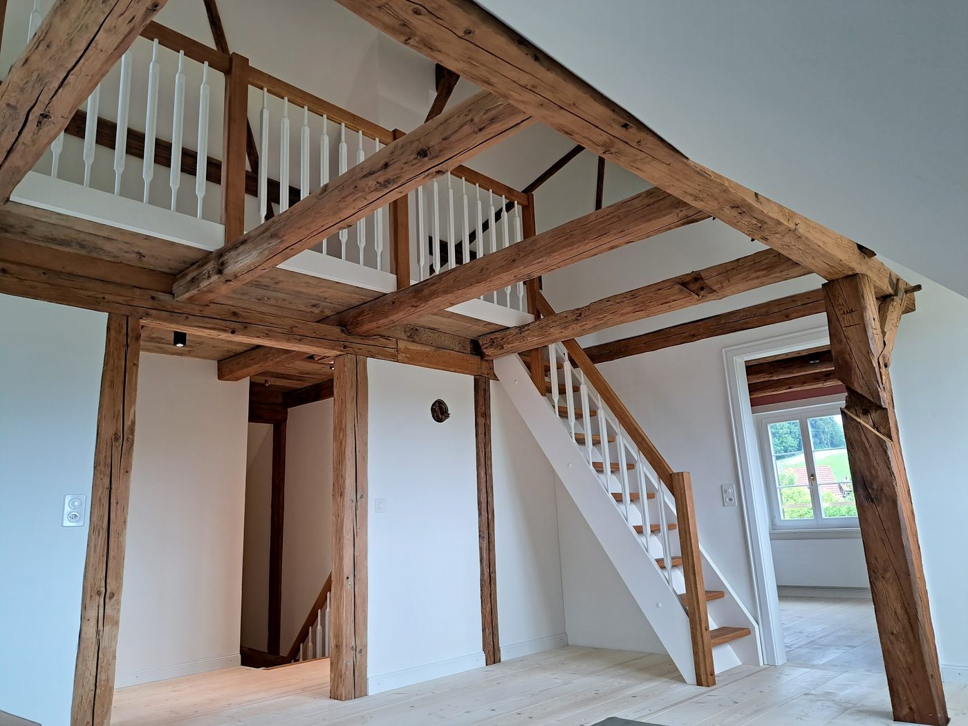 Fachwerk-Innenraum mit weissen Wänden und weisser Treppe