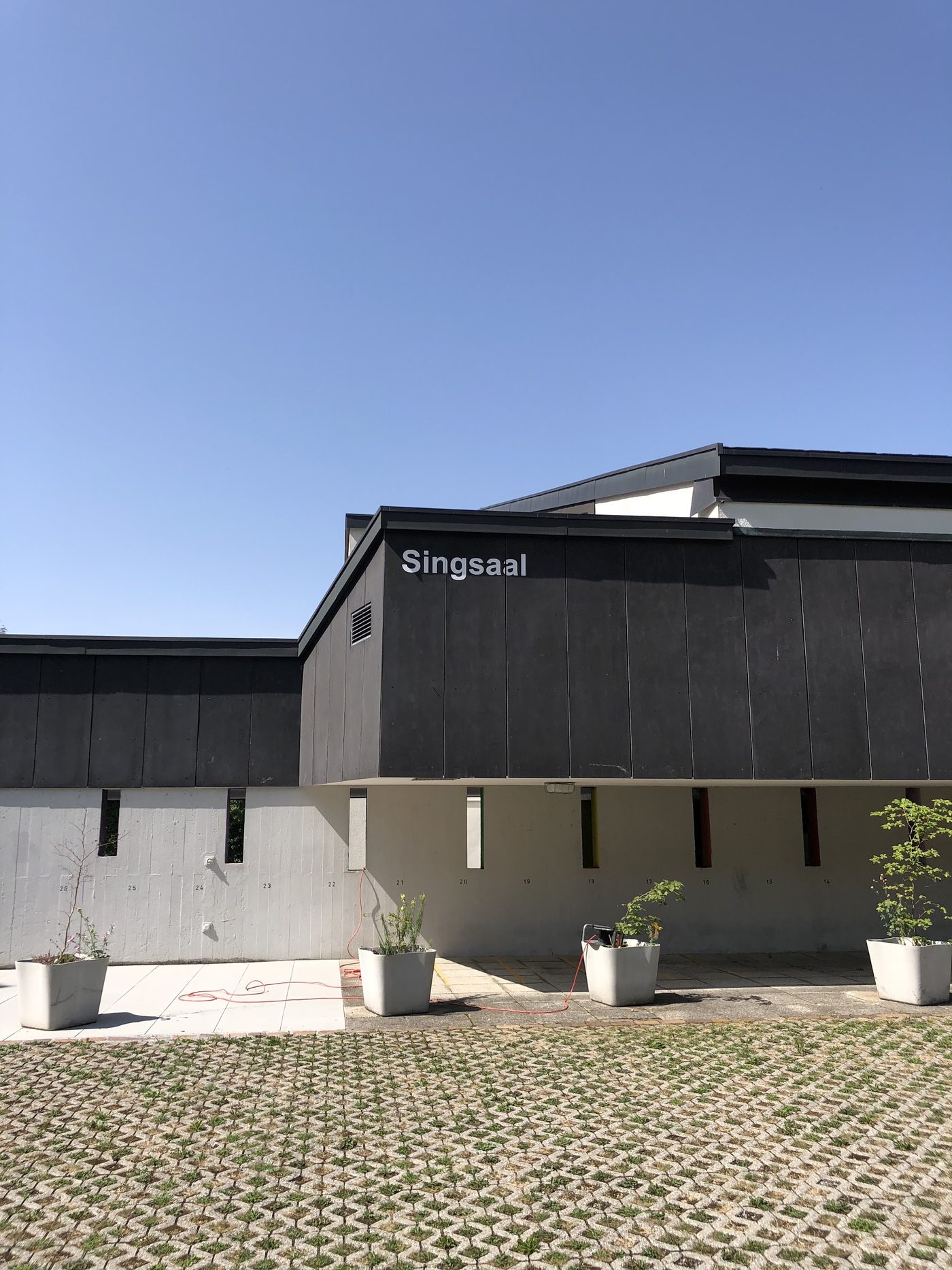 Dunkel gestrichene Gebäudefassade mit der Aufschrift Singsaal