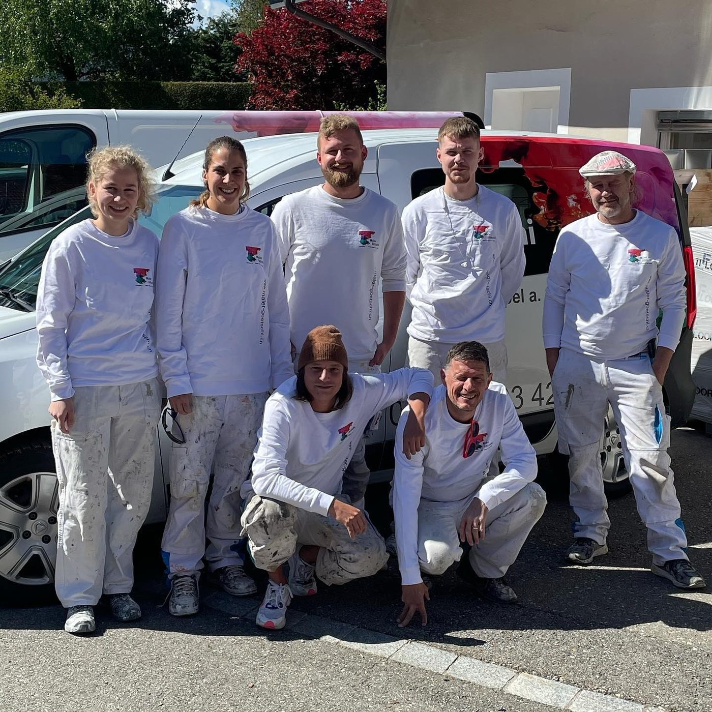 Das Team von Maler Götschi in weissen Überkleidern vor dem Firmenwagen