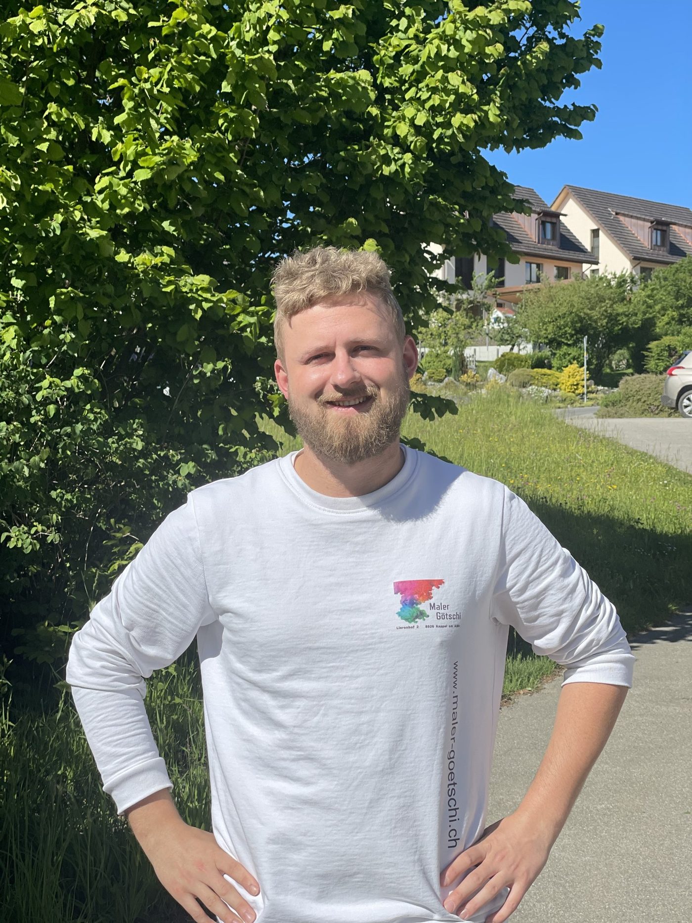 Mitarbeiter im weissen Götschi-Pullover mit Logo und Webadresse